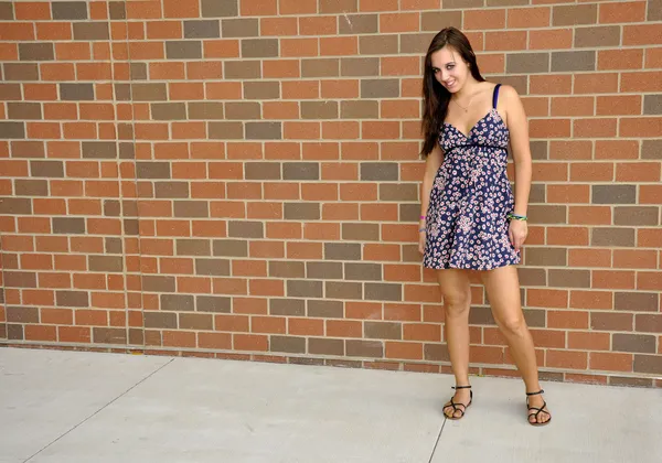 Chica adolescente de pie junto a una pared de ladrillo — Foto de Stock