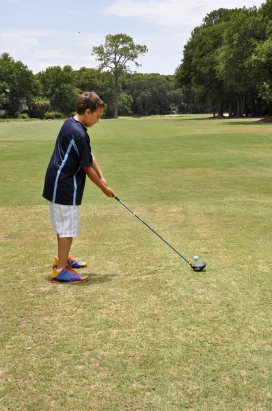 Jovem rapaz dirigindo uma bola de golfe — Fotografia de Stock