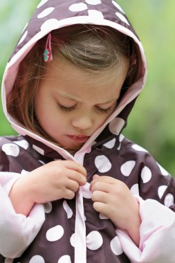 Child Putting on Raincoat clipart