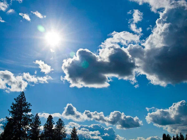 Sol brilhante e nuvens brancas em um céu azul — Fotografia de Stock