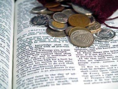 The Bible opened to the Book of Proverbs with Coins clipart