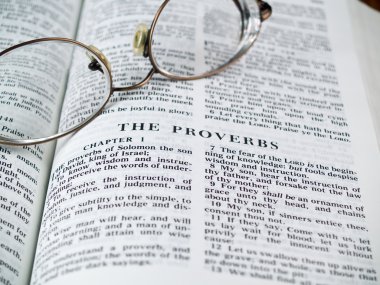 The Bible opened to the Book of Proverbs with Glasses clipart