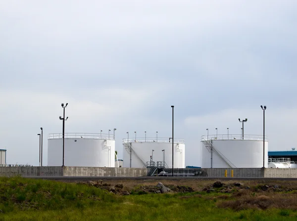 stock image White fuel tanks in a field with an overcast sky