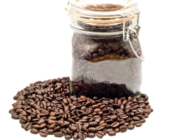 Granos de café y un recipiente de vidrio transparente con más café — Foto de Stock