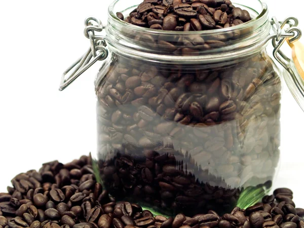 Kaffebønner og en beholder av klart glass med mer kaffe – stockfoto