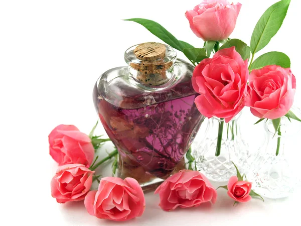Rosas rosadas suaves arregladas con aceite de masaje en una escena romántica —  Fotos de Stock