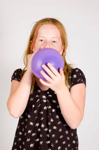 Meisje is blazen op een ballon — Stockfoto