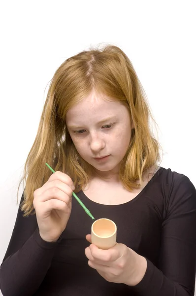 Redhead girl is painting an egg holder — Stock Photo, Image