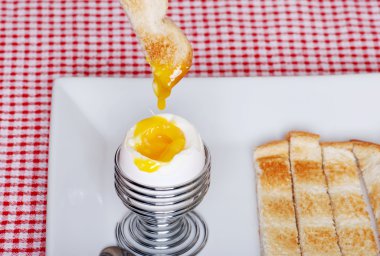 Dipping toast in soft boiled egg clipart