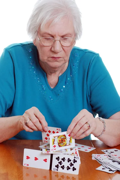 Seniorin bastelt Haus mit Karten — Stockfoto