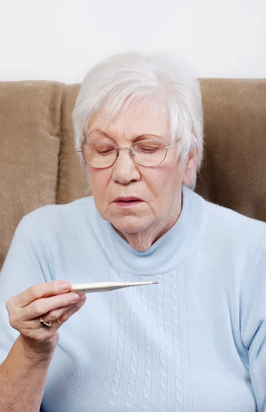 Starszy kobieta czytania termometr — Zdjęcie stockowe