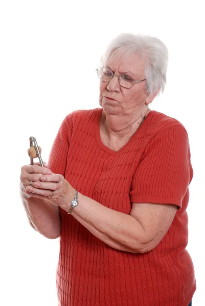 Senior woman struggling to crack walnut — Stock Photo, Image