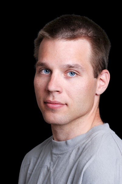 Portrait of a young man wearing grey t shirt on black background