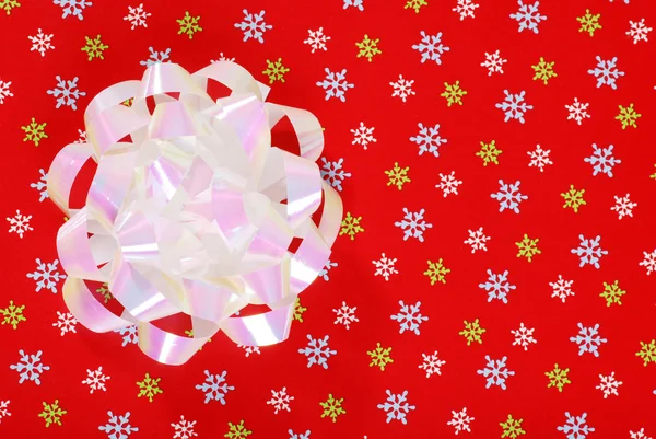 Weihnachtsschleife auf rotem Schneeflockenpapier — Stockfoto