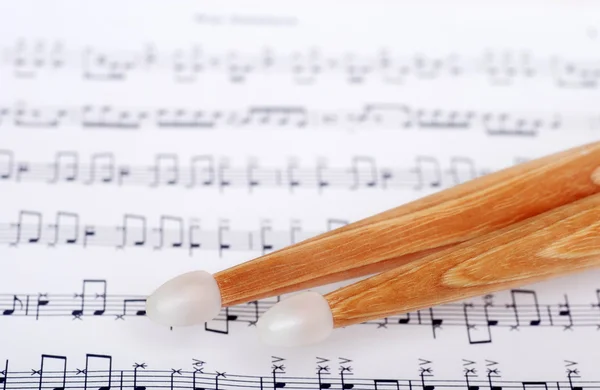 Drum sticks on sheet music — Stock Photo, Image