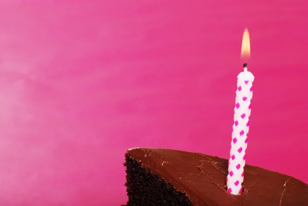 Candela di compleanno di primo piano in fetta di torta al cioccolato Immagine Stock