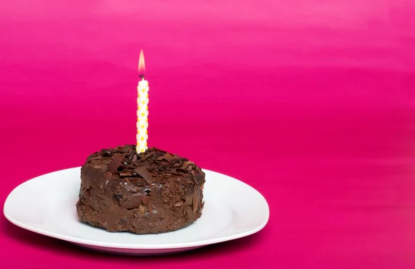Pequeño pastel de chocolate con vela de cumpleaños en un plato —  Fotos de Stock
