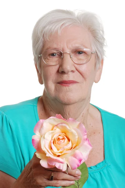 Sorrindo mulher sênior segurando falso rosa foco na flor — Fotografia de Stock