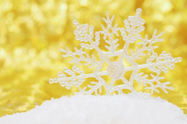 Snöflinga i snö med guld bakgrund — Stockfoto