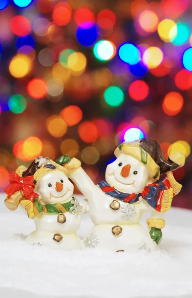 Two snowman with christmas lights in the background — Stock Photo, Image