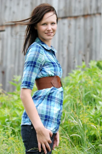Młoda kobieta stoi w polu stodole za nią — Zdjęcie stockowe