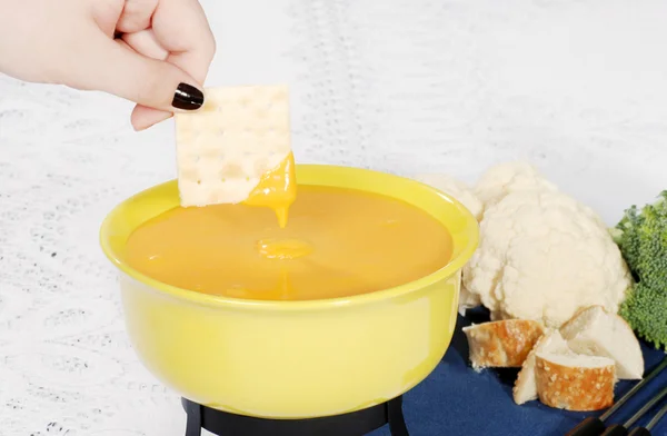 Cracker dipped in cheese fondue — Stock Photo, Image