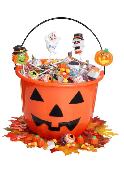 Child halloween pumpkin bucket with candy and fall leaves — Stock Photo, Image