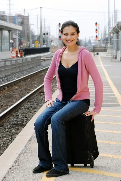Woman sitting on luggage waiting for train — Stock Photo, Image