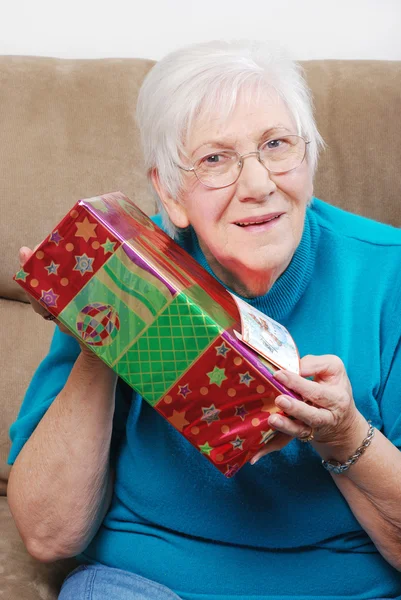Felice donna anziana scuotendo il suo regalo di Natale — Foto Stock