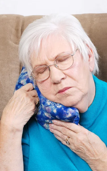 Donna anziana che utilizza pacchetto caldo erba medica — Foto Stock