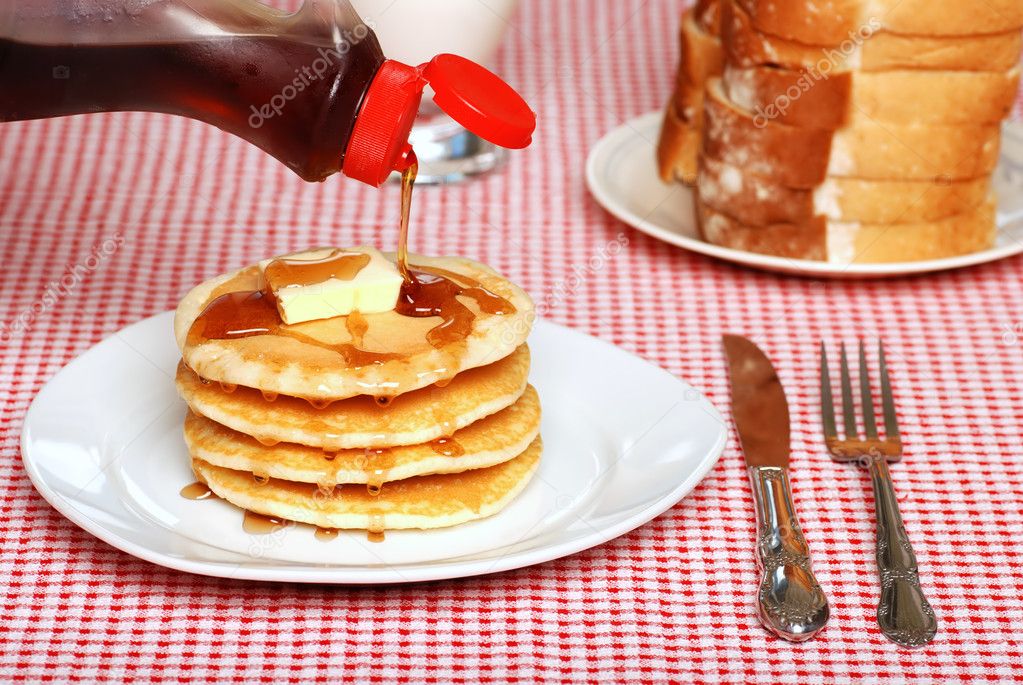 Maple Syrup being poured on a stack of pancakes
