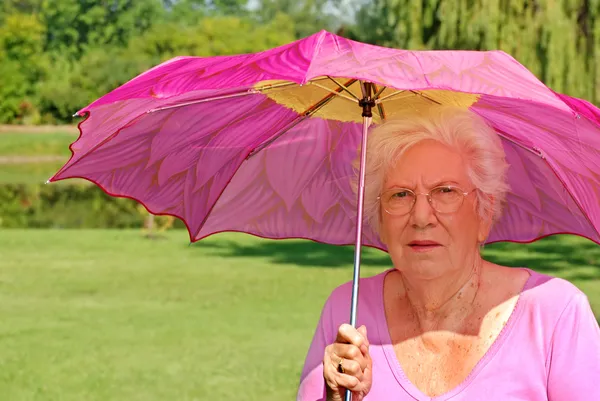 Старшая женщина с красочным зонтиком — стоковое фото
