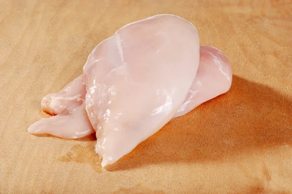 Uncooked chicken breast on wooden cutting board — Stock Photo, Image