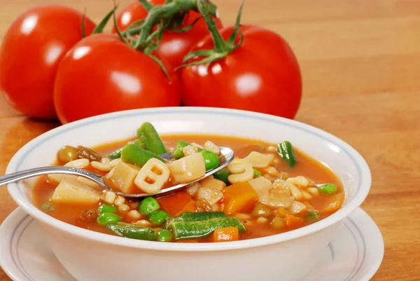 Zeleninová polévka s rajčaty v pozadí — Stock fotografie