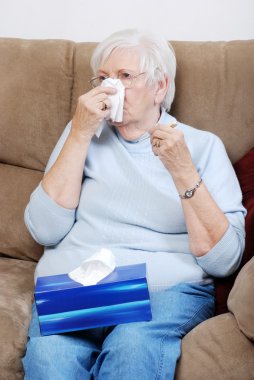 Sick senior woman blowing her nose clipart