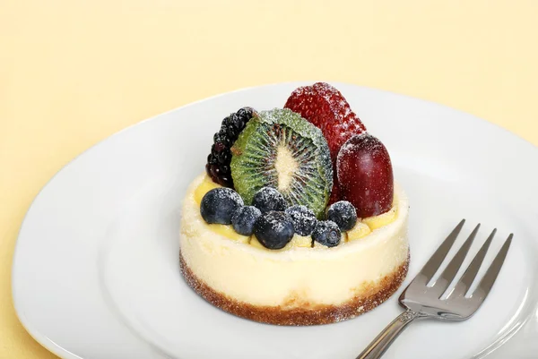 Торт с фруктовым сыром на тарелке с вилкой — стоковое фото