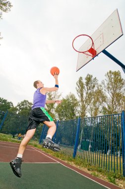 Young men playing street basketball at court playground clipart