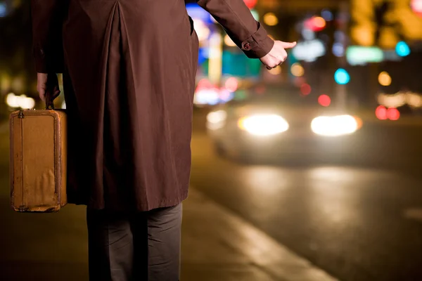 Um hitchhiker com uma mala velha está esperando em uma calçada como ni — Fotografia de Stock