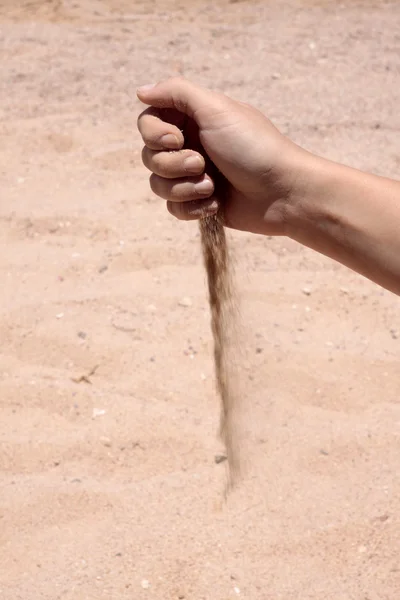 La main de la femelle verse du sable au bord de la mer — Photo