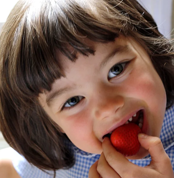 Niedliche Mädchen essen Erdbeere Stockbild