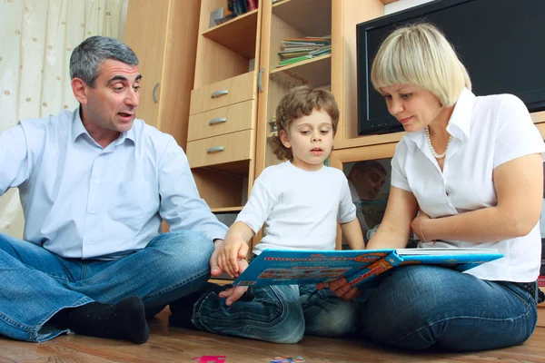 Мужчина, женщина и маленький мальчик читают книгу — стоковое фото