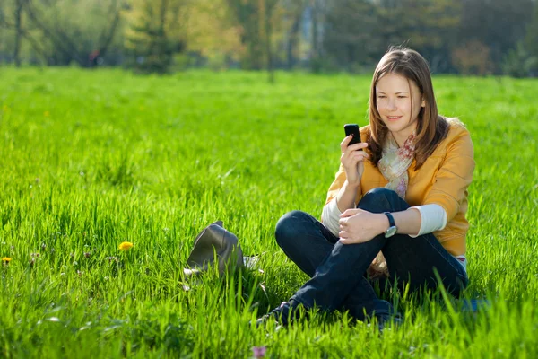 Kobieta na telefon komórkowy w parku — Zdjęcie stockowe