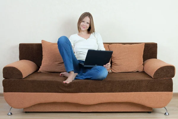 Γυναίκα με φορητό υπολογιστή στον καναπέ — Φωτογραφία Αρχείου