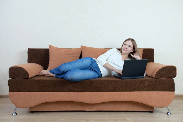 Kvinna med laptop på soffan Stockbild