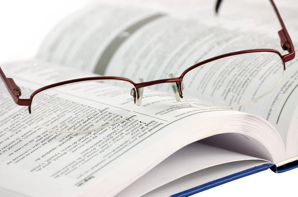 Ordbok med glasögon på vita — Stockfoto