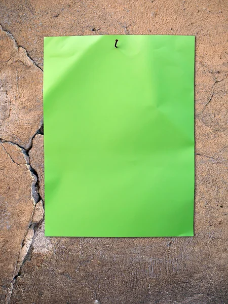 Зеленая бумага на старой стене — стоковое фото