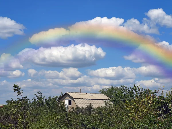 Regenboog en zomers bewolkte hemel — Stockfoto
