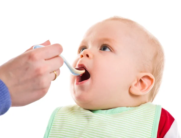 Mother spoon-feeds the child. Royalty Free Stock Images