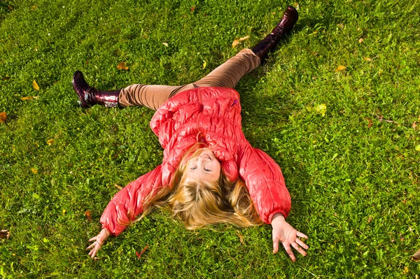 Glückliches kleines Mädchen auf dem Gras liegend Stockbild