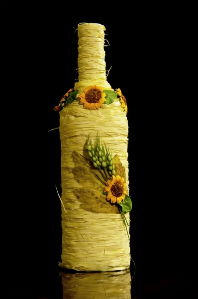 Wijnfles verpakt in gele touw met decoratieve bloemen — Stockfoto